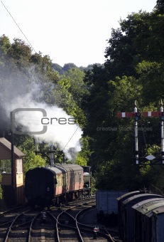 Steam train pulling carriages away from station