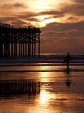 surfer at sunset by pier 