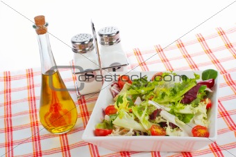 Oil bottle, green salad, salt and pepper