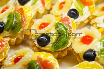 Fruit cakes with pineapple, kiwi and grape berry on on top. Shallow DOF.