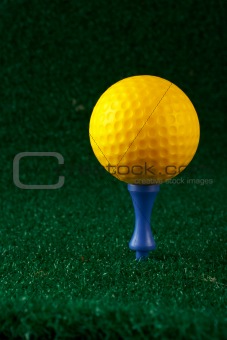 Yellow golfball and blue tee