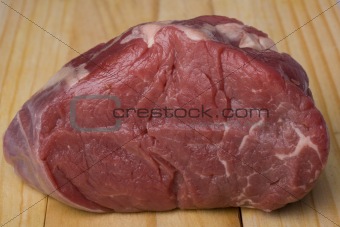 piece of raw meat on a wooden chopping board