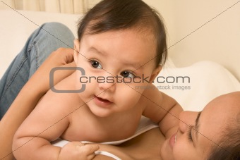 Mother playing with her baby boy son on bed