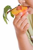 Closeup of kid eating a half peach