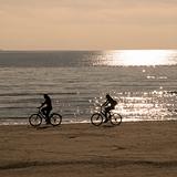 two people riding bicycles along beach