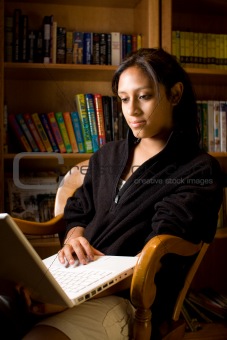 Young hispanic girl working on a laptop at the library