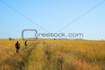 Two bike tourist on yellow field rural road in the morning