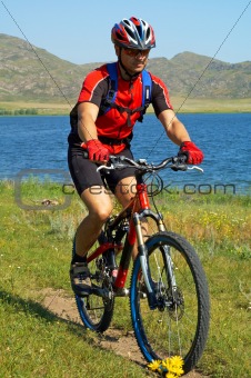 Bike tourist on green field beside lake