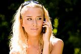 Smiling blond young woman talking on mobile phone outdoors
