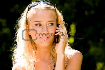 Smiling blond young woman talking on mobile phone outdoors