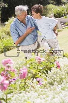 Grandfather and grandson outdoors in garden talking and smiling