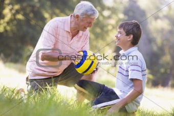 Grandfather and grandson at a park with a ball smiling
