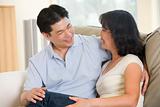 Couple relaxing in living room talking and smiling