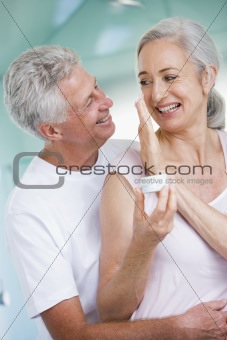 Couple embracing at a spa holding cream and smiling