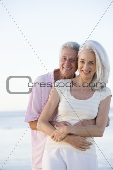 Couple at the beach embracing and smiling