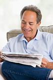 Man relaxing with a newspaper smiling