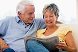 Couple in living room reading newspaper smiling
