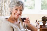 Woman in living room with glass of wine smiling