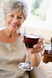 Woman in living room with glass of wine smiling