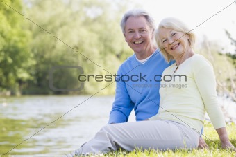 Couple outdoors at park by lake smiling