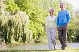 Couple walking outdoors at park by lake smiling