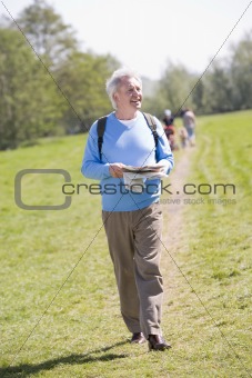 Man walking outdoors holding map smiling with people in backgrou