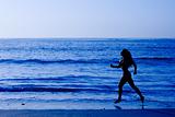 Healthy life concept - sporty woman running along beach