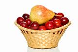 Wicker basket with cherry plums and yellow-red pear