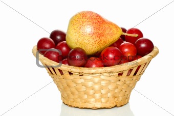 Wicker basket with cherry plums and yellow-red pear