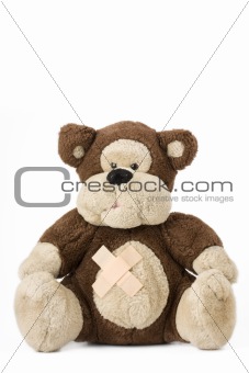 classsical teddy bear with bandaids sitting on a white background