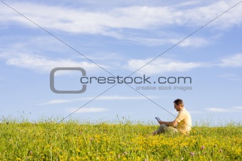 Man with laptop on meadow