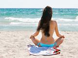 young girl meditating on sand beach