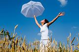 Happy young girl with umbrella in the field
