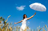 Happy young girl with umbrella in the field.