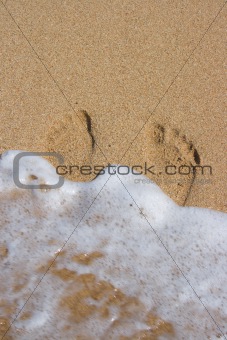 Wave surging on footpints on sand