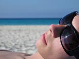 girl with sunglasses tanning on the beach