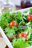 Green salad with tomatoes and a wooden spoon