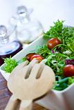 Green salad with tomatoes and a wooden spoon