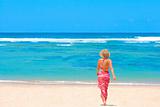 Girl in bikini and pareo walking towards ocean