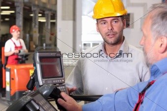 male engineer talking to forklift operator