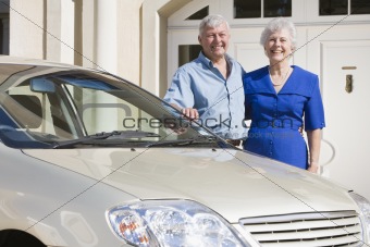 Senior couple standing to new car
