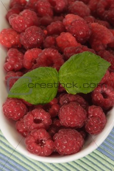 Raspberries with leaves on a plate