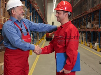 two workers handshake in warehouse