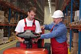 A senior worker teaching his junior the operation of a fork lift vehicle in a factory