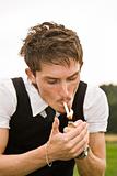Young man lighting a cigarette outdors