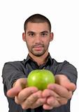 Handsome young man smiling holding a green apple in the palm of his hands.