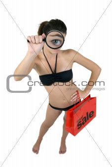 sexy bikini magnifying her eye holding a sale shopping bag .