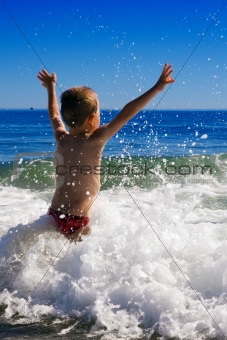 young child playing in the waves