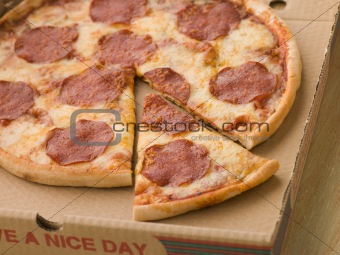 Pepperoni Pizza in a Take Away Box with a Cut Slice