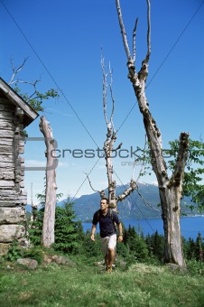 Man hiking up to a wooden cabin